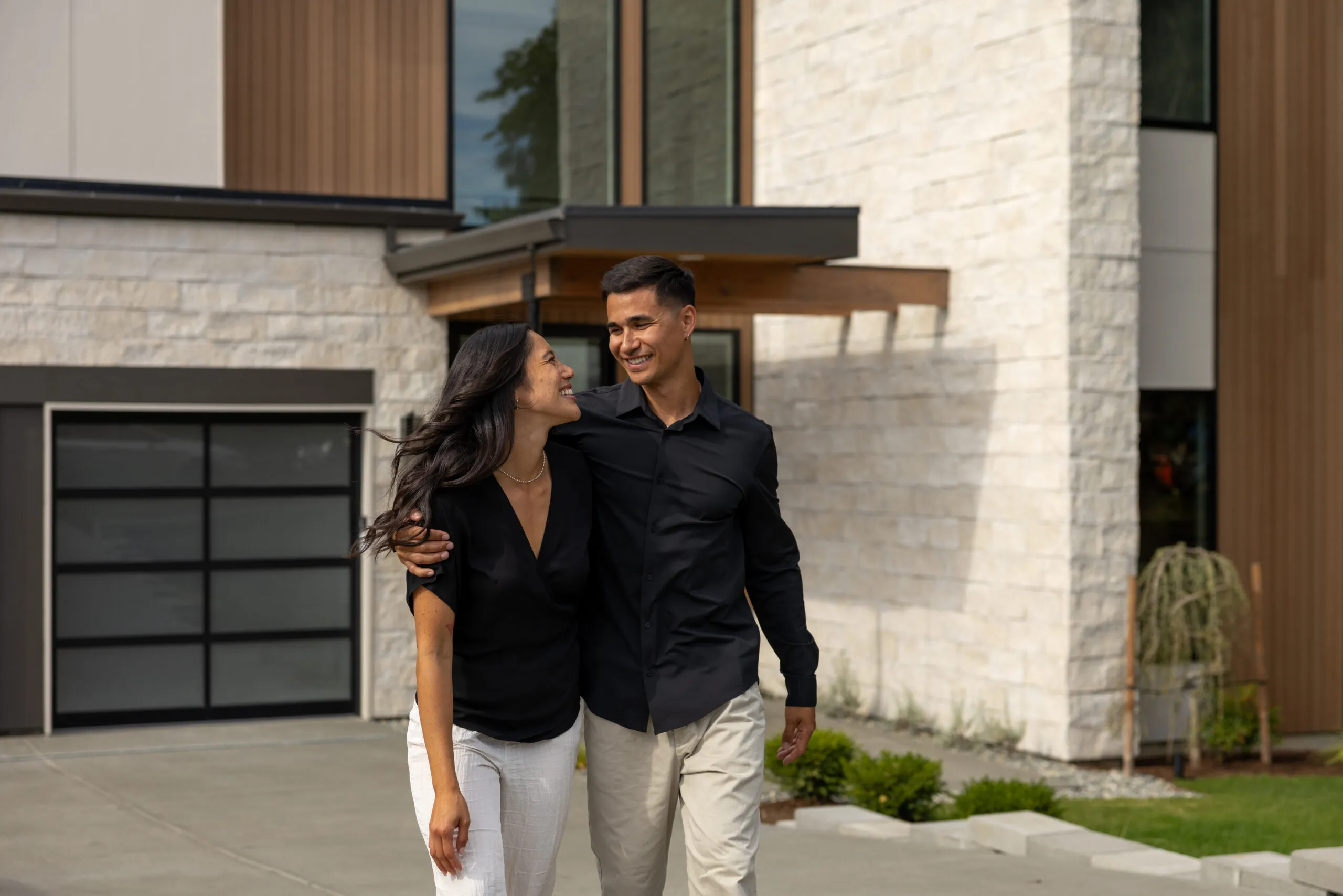 Happy couple walking out of their home across the driveway.